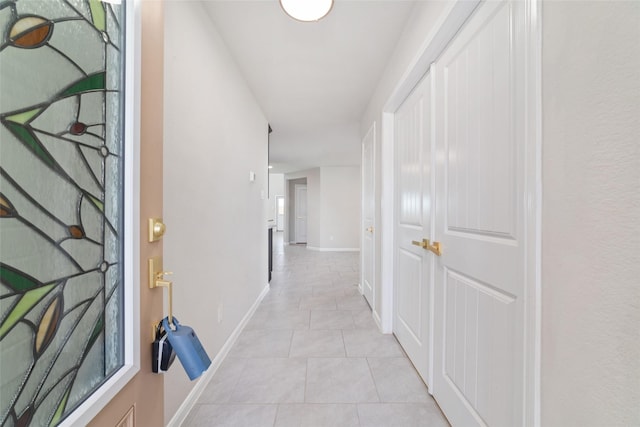 hallway featuring light tile patterned floors and baseboards