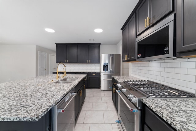 kitchen featuring a sink, stainless steel appliances, light stone countertops, and light tile patterned flooring