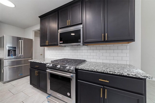 kitchen featuring tasteful backsplash, light tile patterned flooring, high end appliances, and light stone countertops