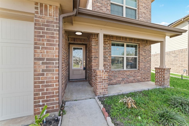 view of exterior entry with brick siding and covered porch