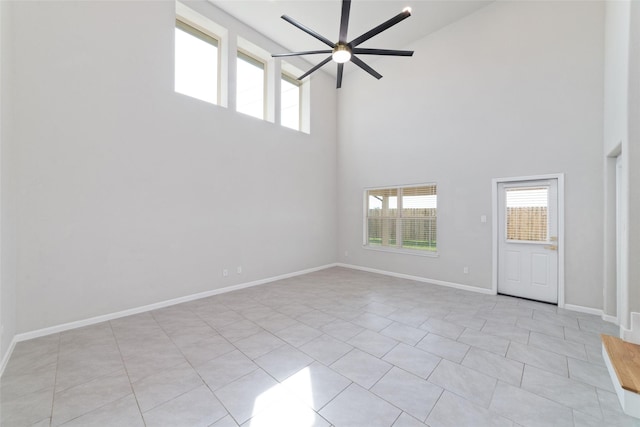 spare room featuring plenty of natural light, baseboards, ceiling fan, and a towering ceiling