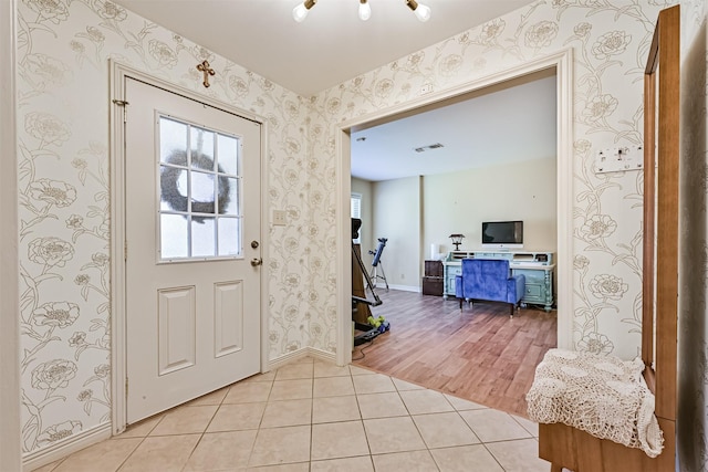 foyer entrance with light tile patterned flooring, wallpapered walls, and baseboards