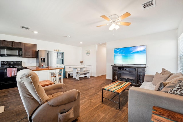 living room with visible vents, baseboards, dark wood-type flooring, and a ceiling fan