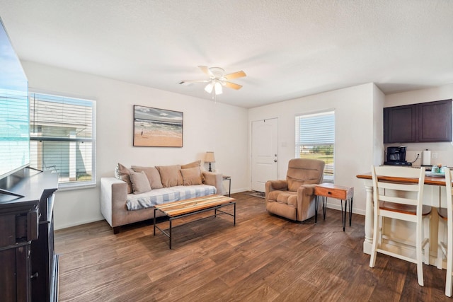 living room featuring dark wood-style floors, a textured ceiling, baseboards, and ceiling fan