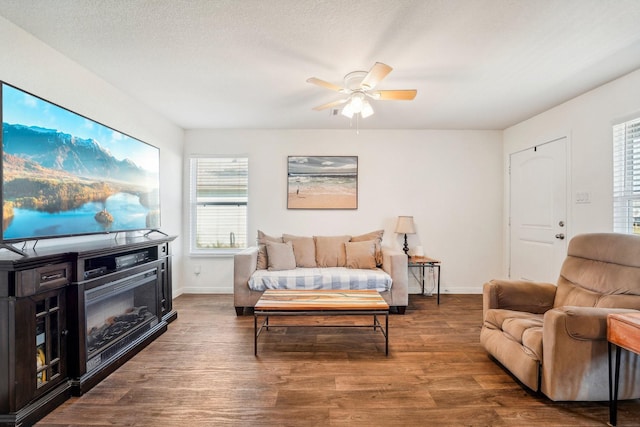 living room with a ceiling fan, wood finished floors, baseboards, and a textured ceiling