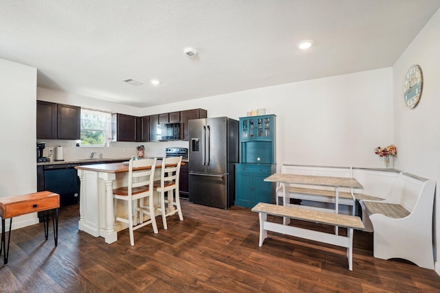 kitchen with dark brown cabinets, visible vents, dark wood-type flooring, and black appliances