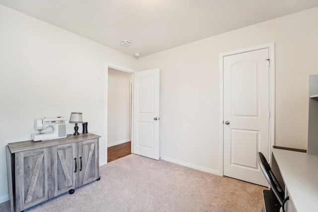 home office with baseboards and light carpet