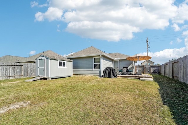 rear view of property with a yard, an outdoor structure, a fenced backyard, and a shed