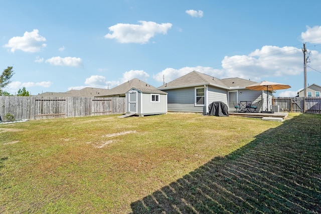 view of yard with an outbuilding, a deck, a storage shed, and a fenced backyard