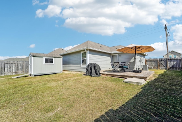 back of property with an outbuilding, a storage unit, a fenced backyard, and a lawn