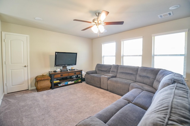 living area featuring visible vents, carpet flooring, and a ceiling fan