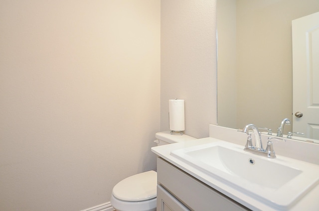 bathroom with toilet, vanity, and baseboards