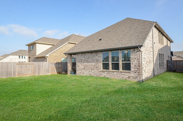 rear view of property featuring a lawn, a fenced backyard, and brick siding