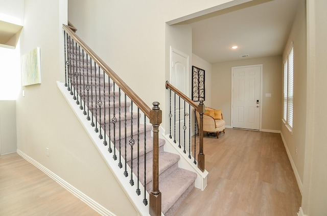 stairway featuring visible vents, recessed lighting, baseboards, and wood finished floors