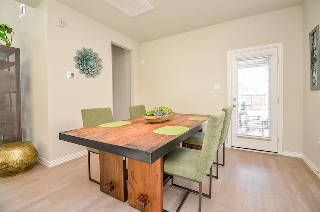 dining space featuring visible vents, light wood-type flooring, and baseboards