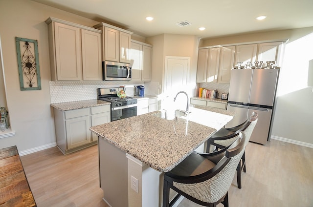 kitchen featuring visible vents, appliances with stainless steel finishes, light wood-style floors, and a sink