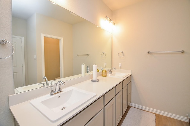 full bath with a sink, baseboards, and double vanity