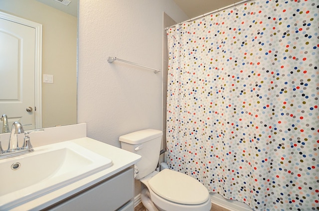 bathroom featuring toilet, vanity, a shower with shower curtain, and a textured wall