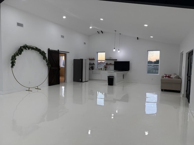 unfurnished living room with a barn door, visible vents, and a wealth of natural light