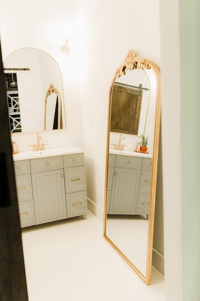 bathroom featuring a sink, baseboards, and two vanities