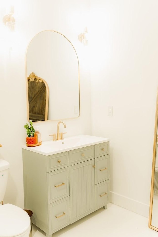 bathroom with toilet, vanity, and baseboards