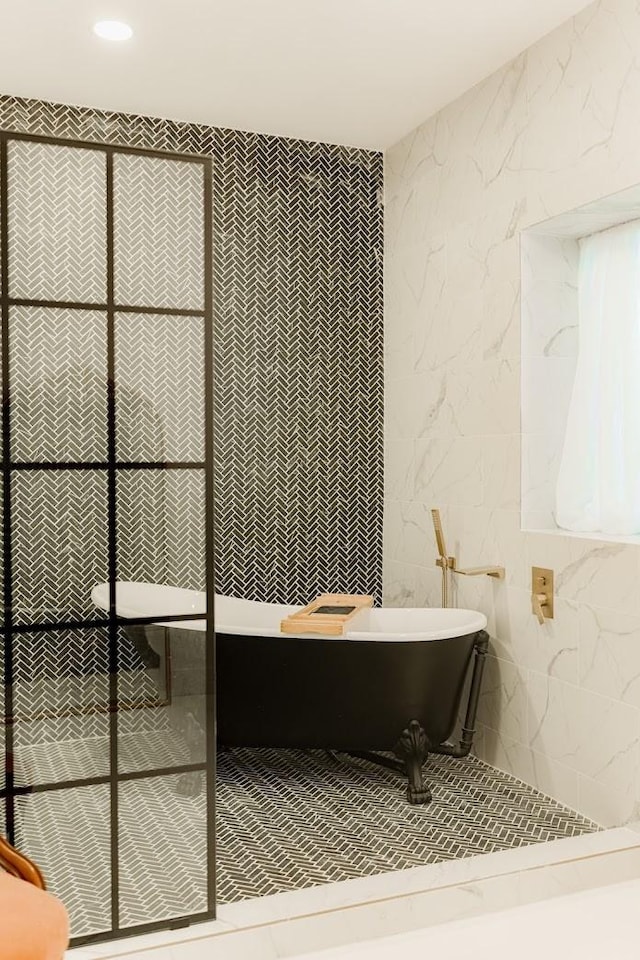 bathroom featuring a soaking tub, recessed lighting, and tile walls