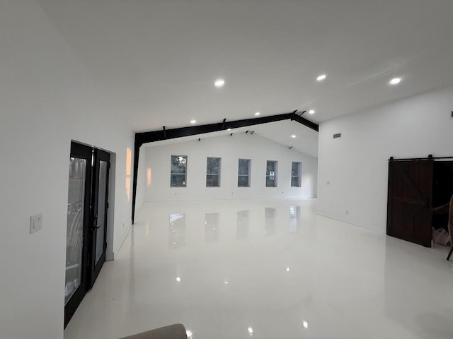 interior space with lofted ceiling with beams, a barn door, and recessed lighting