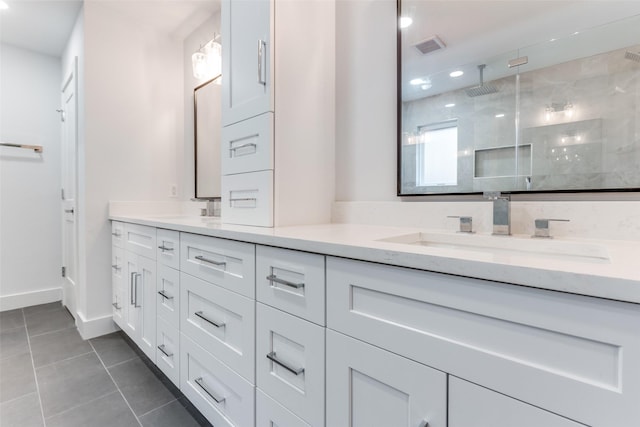 bathroom with visible vents, double vanity, a tile shower, a sink, and tile patterned floors