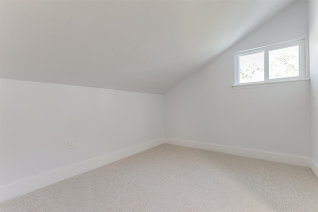 bonus room featuring baseboards, light colored carpet, and lofted ceiling