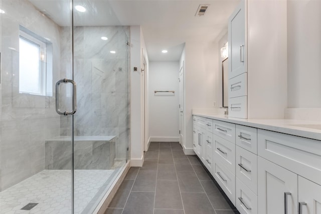 bathroom featuring tile patterned flooring, a shower stall, baseboards, double vanity, and recessed lighting