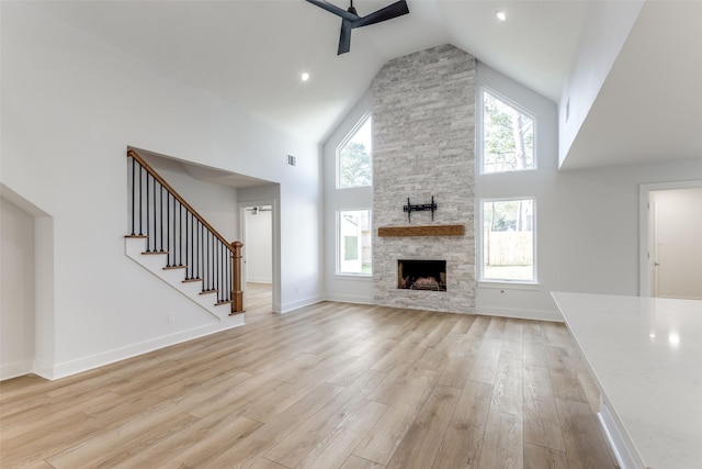 unfurnished living room featuring baseboards, high vaulted ceiling, light wood-type flooring, and a ceiling fan