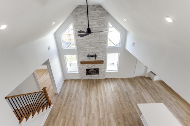 unfurnished living room featuring wood finished floors, baseboards, visible vents, high vaulted ceiling, and a fireplace