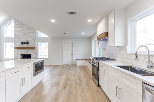 kitchen with visible vents, backsplash, stainless steel appliances, white cabinetry, and a sink