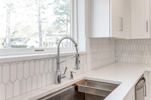 interior details with a sink, decorative backsplash, and white cabinets