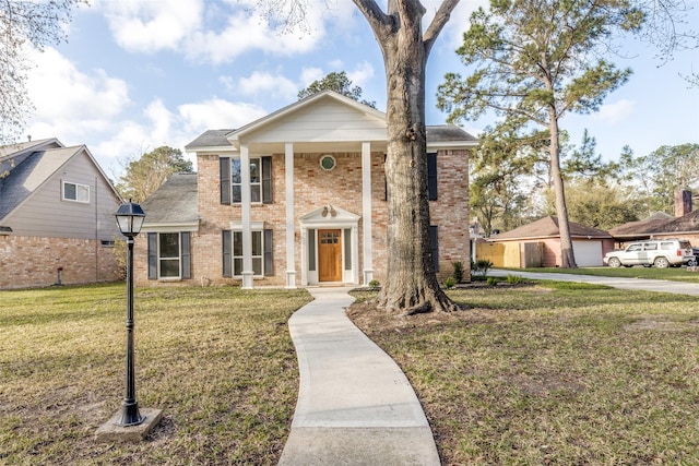 greek revival inspired property with brick siding and a front yard