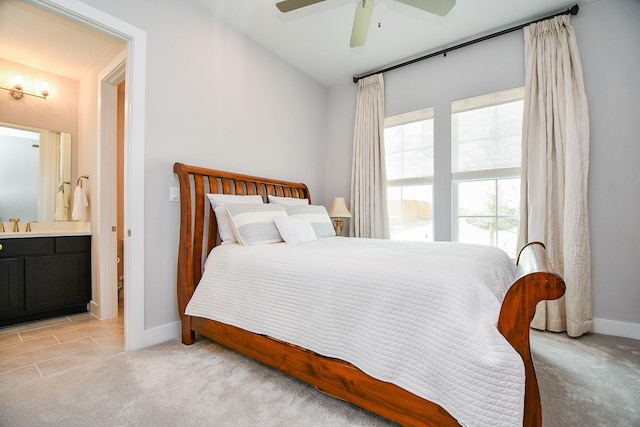 bedroom with light carpet, ceiling fan, ensuite bath, and baseboards