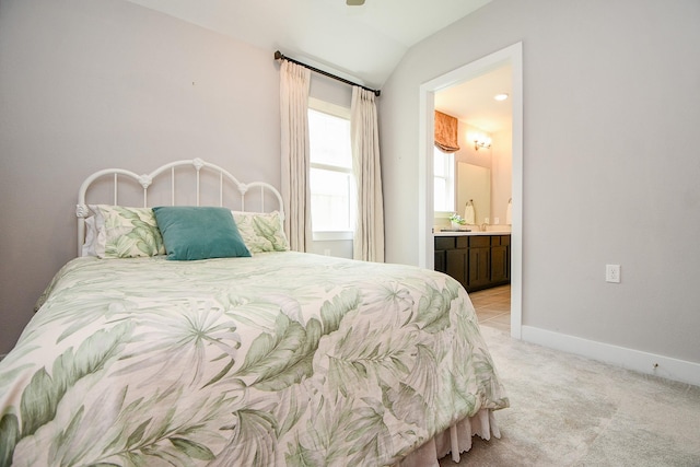 bedroom with connected bathroom, baseboards, light colored carpet, and lofted ceiling