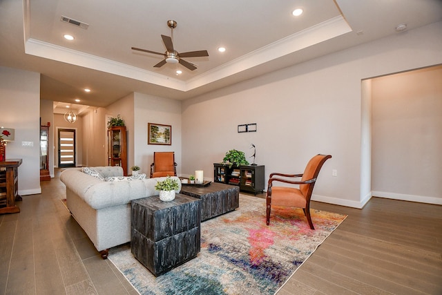 living area featuring visible vents, a raised ceiling, and a ceiling fan