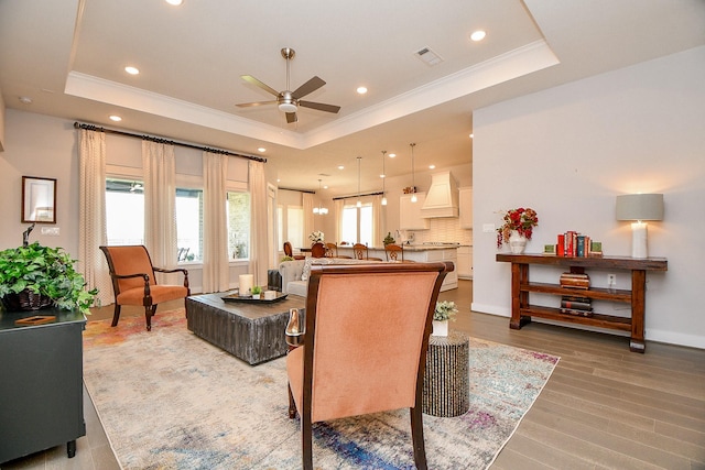 living room featuring a raised ceiling, crown molding, and ceiling fan