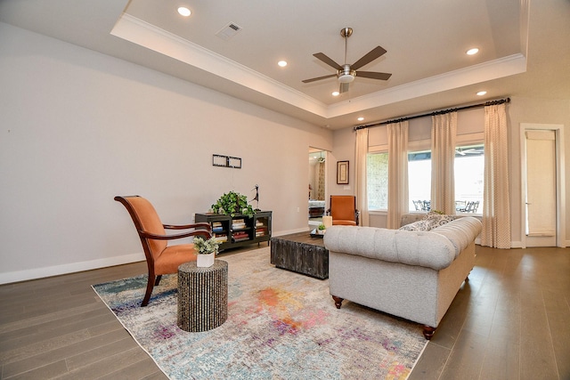 living area with visible vents, wood finished floors, crown molding, a raised ceiling, and ceiling fan