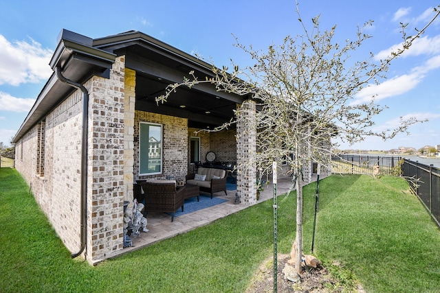 rear view of property featuring brick siding, an outdoor hangout area, a yard, a fenced backyard, and a patio