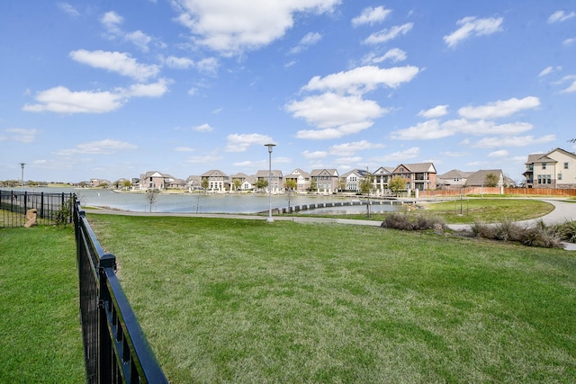 view of yard featuring a residential view, a water view, and fence