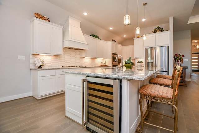 kitchen with tasteful backsplash, wine cooler, a kitchen breakfast bar, custom exhaust hood, and stainless steel appliances