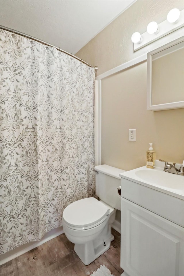 bathroom featuring curtained shower, toilet, vanity, and wood finished floors