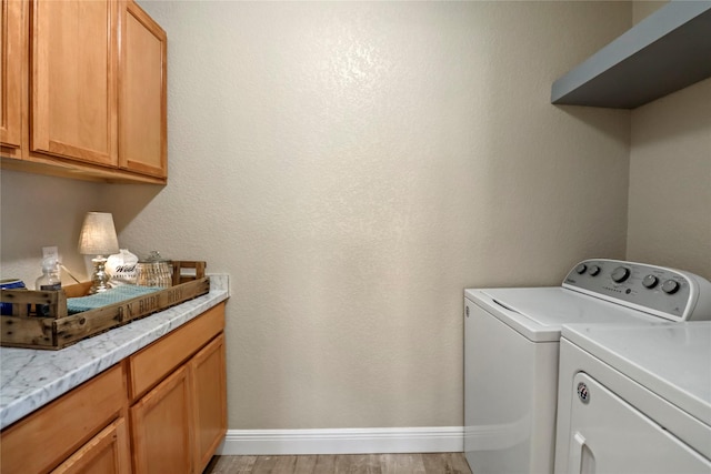 washroom featuring light wood finished floors, baseboards, cabinet space, and washing machine and clothes dryer