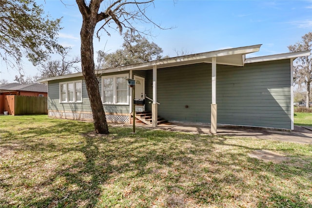 rear view of house featuring a lawn and fence