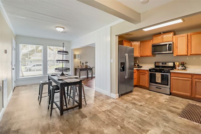 kitchen featuring baseboards, light wood-style flooring, light countertops, appliances with stainless steel finishes, and beamed ceiling