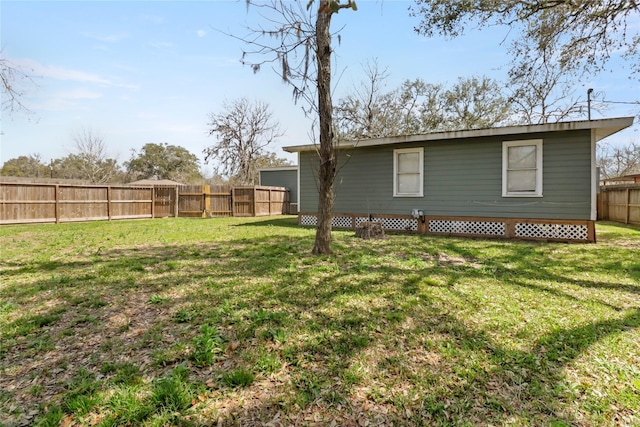 rear view of house featuring a fenced backyard and a lawn