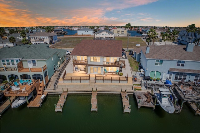 aerial view at dusk featuring a residential view and a water view