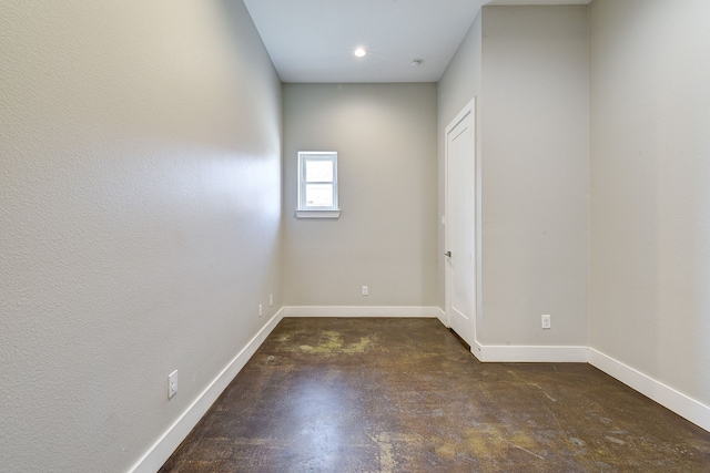 spare room featuring baseboards and concrete flooring